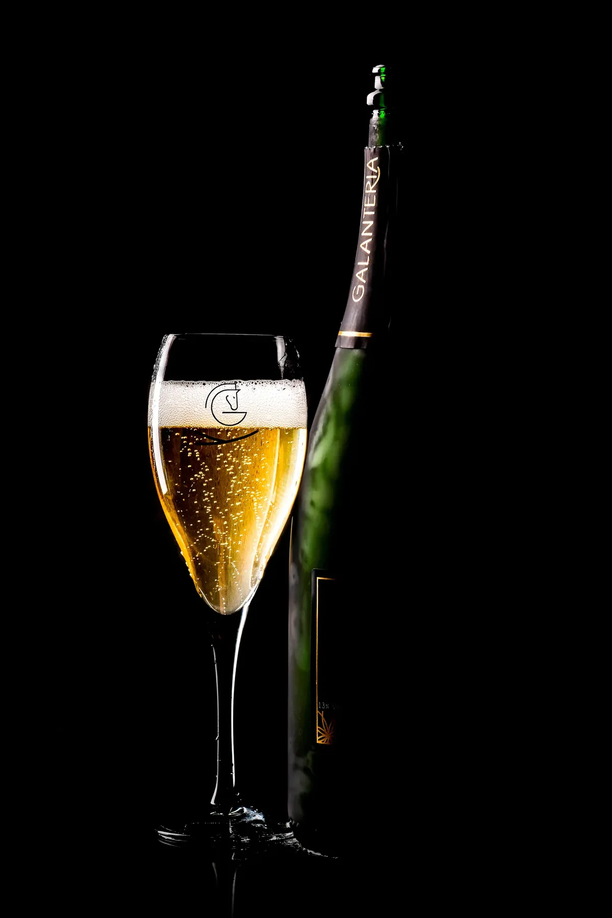 Eine Flasche und ein Glas Galantería, vor schwarzem Hintergrund beleuchtet